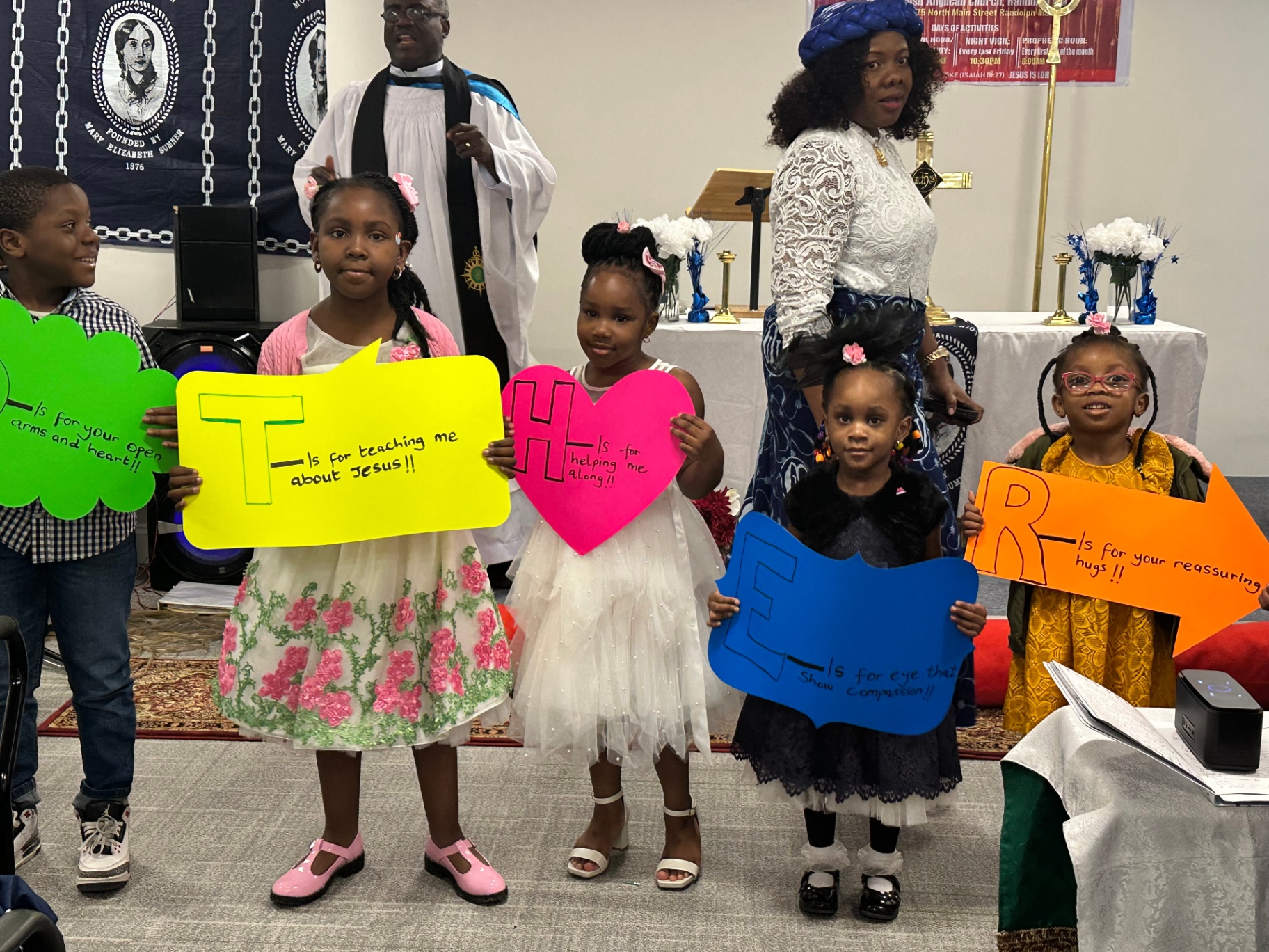 Close-up of children holding T-H-E-R letters honoring mothers