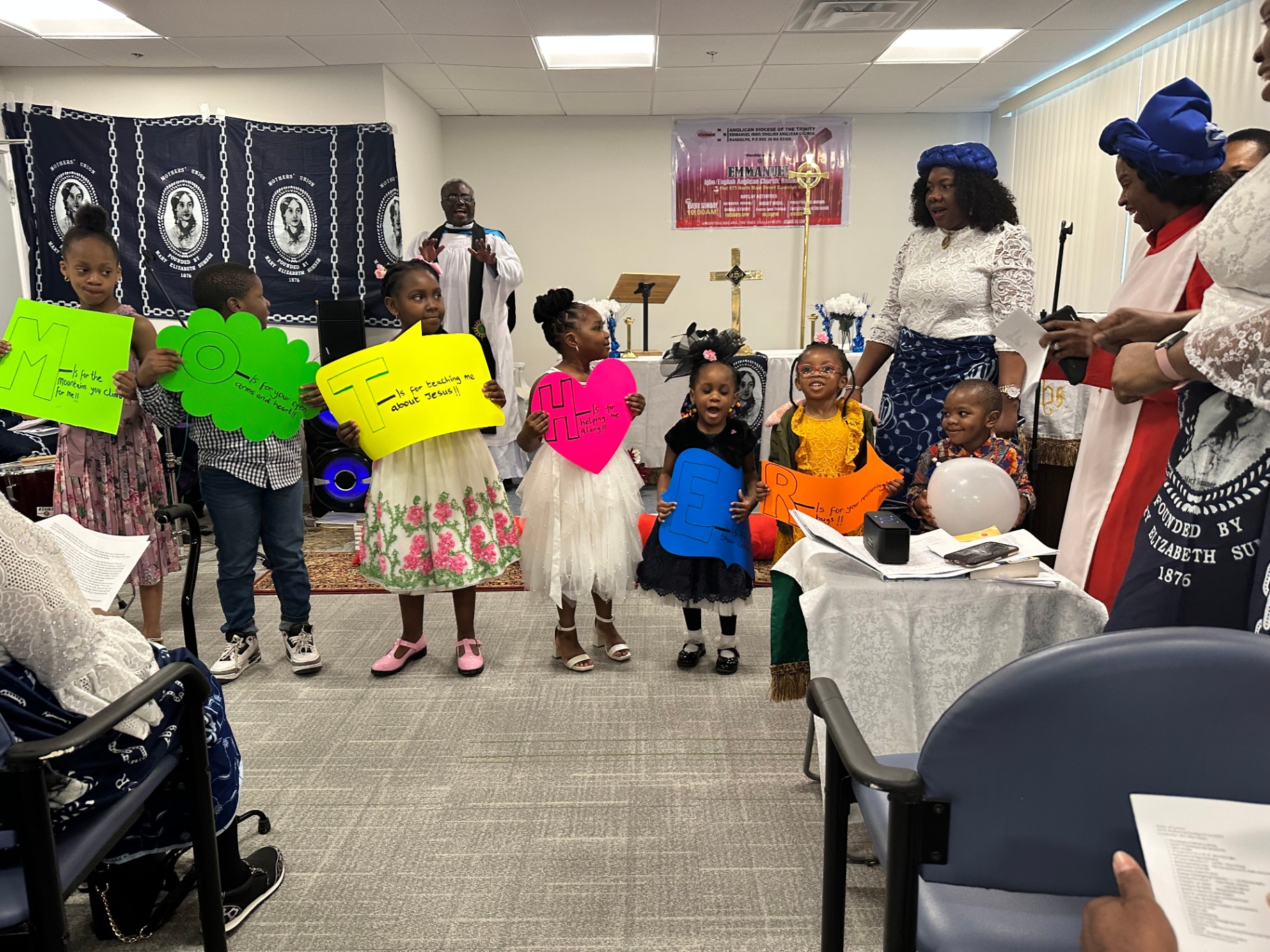 Children spelling out M-O-T-H-E-R with colorful signs during Mother's Sunday 2023